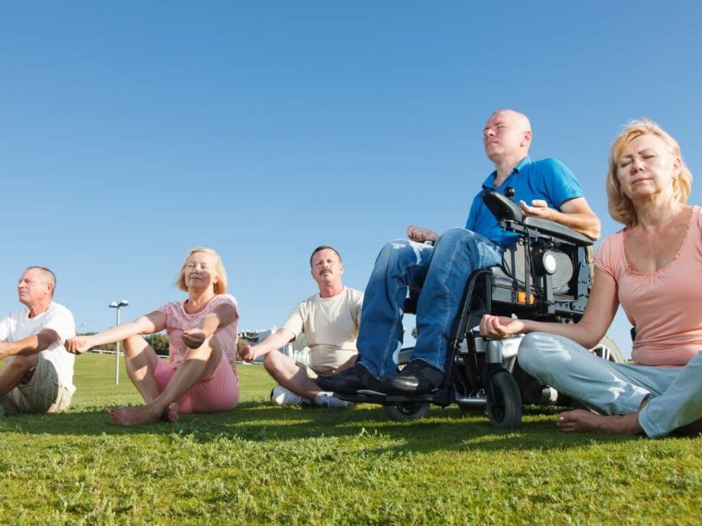 group pf people including wheelchair user doing yoga outside