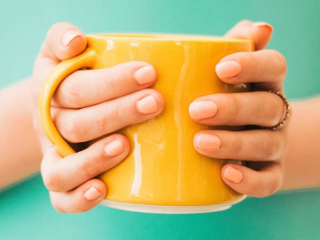 hands holding oragnce mug