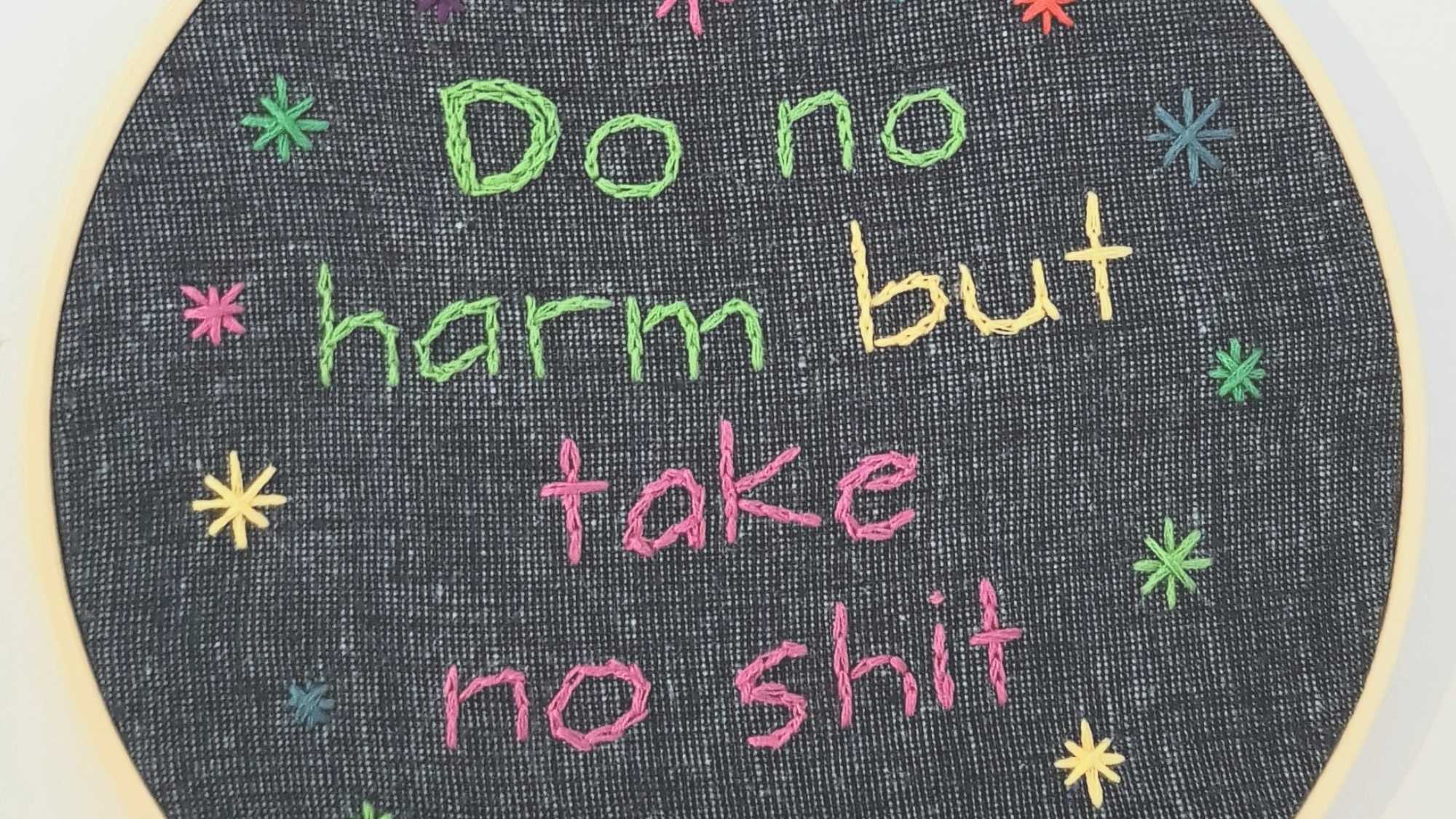 The word "Do no harm but take no shit" embroidered in green, yellow and pink on a dark background