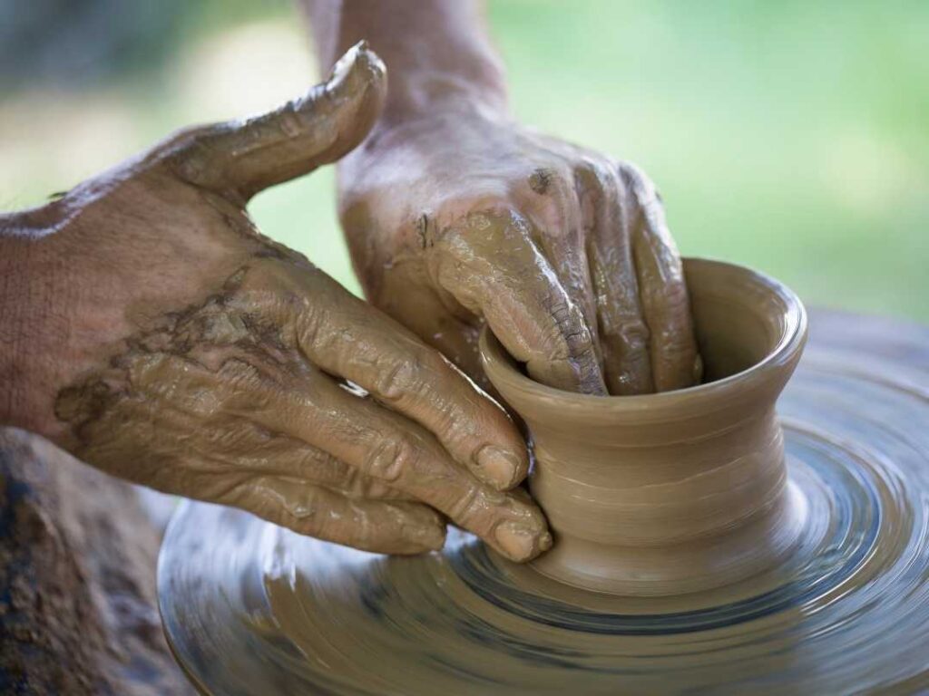 man's hands making pottery on a wheel